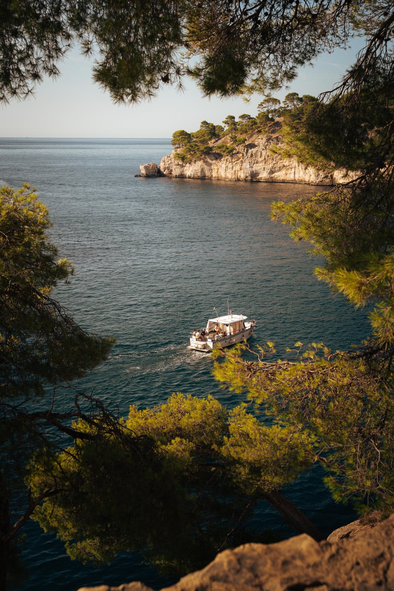 Bateau dans une calanque encadrée de pins